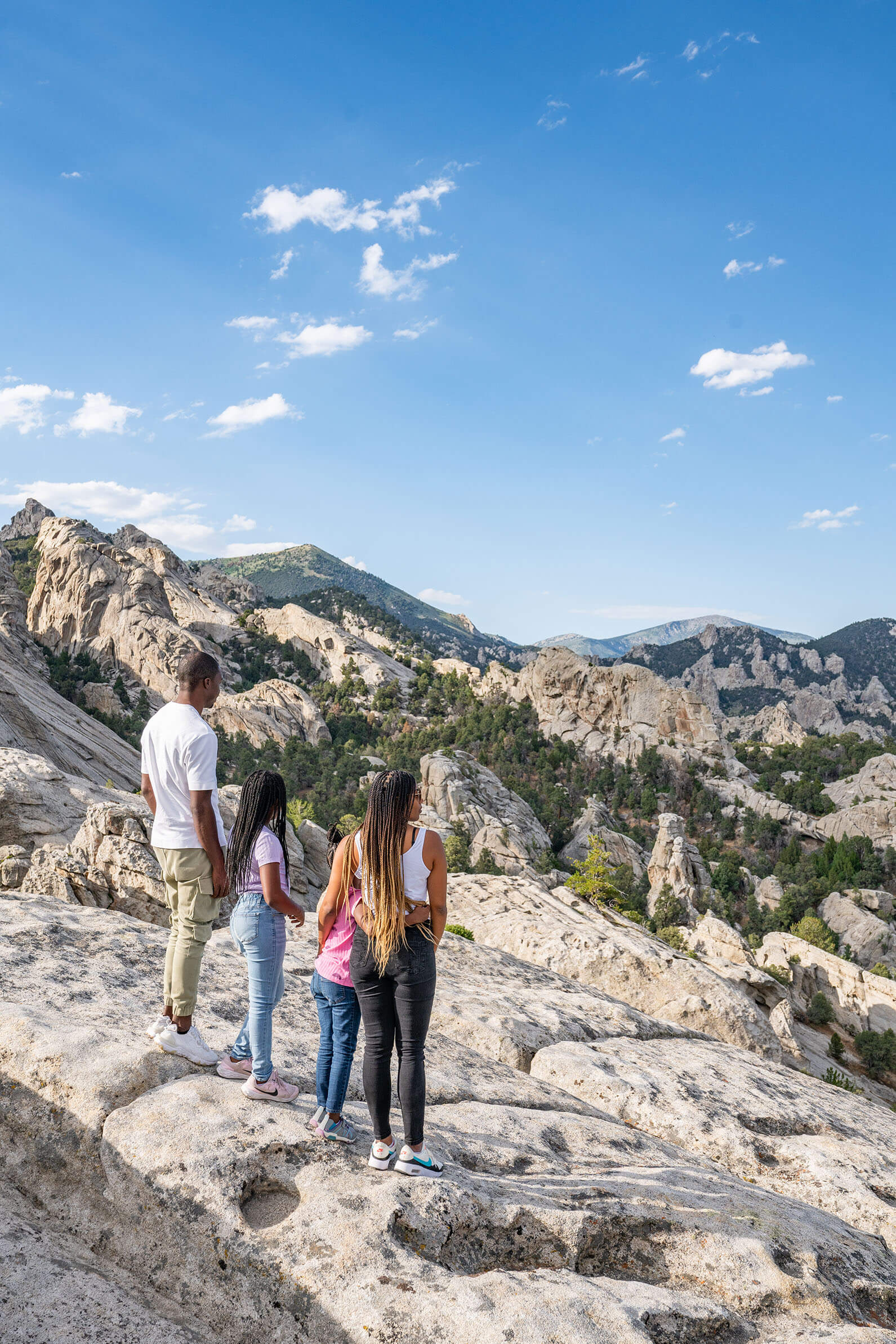 A family of four stand looking out over a scenic view at the City of Rocks.