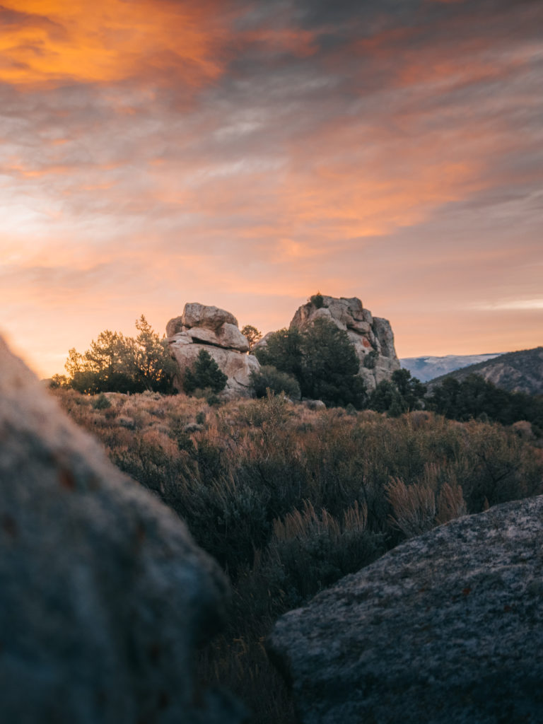 A scenic shot of rock formations and the landscape at City of Rocks National Reserve in southern Idaho with an orange sunset in the sky.